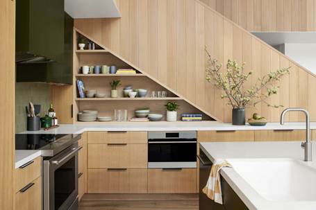 A spotless and organized L-shaped kitchen in Denton, TX, featuring natural wood cabinetry and open shelving built under the stairs, promoting professional move-in ready cleaning.