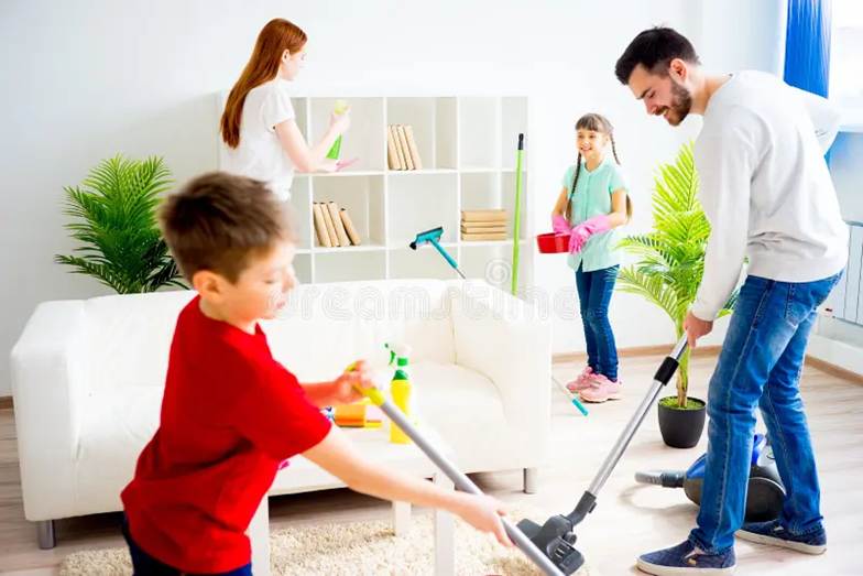 A family of four—a mother, father, daughter, and young son—smiling and cleaning a bright, modern living room together.