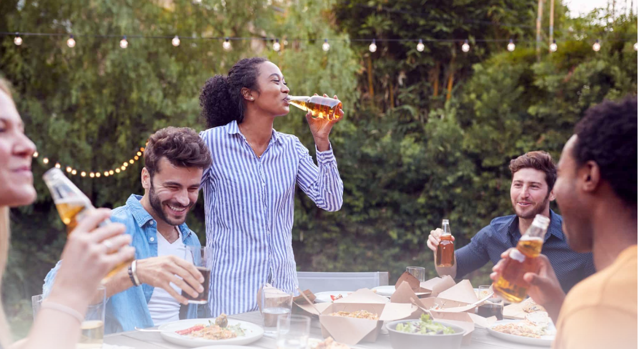 A diverse group of friends laughing and drinking outdoors at a backyard gathering