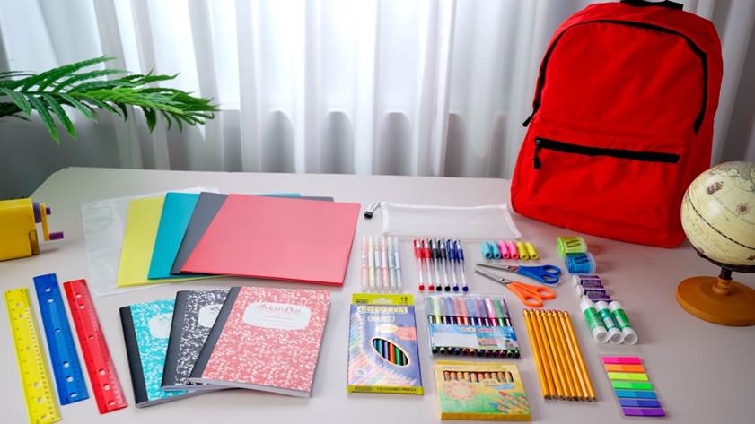 Back-to-School Prep: A Neatly arranged school supplies, including a bright red backpack, colorful folders, composition notebooks, pens, pencils, scissors, and a mini globe on a white desk.