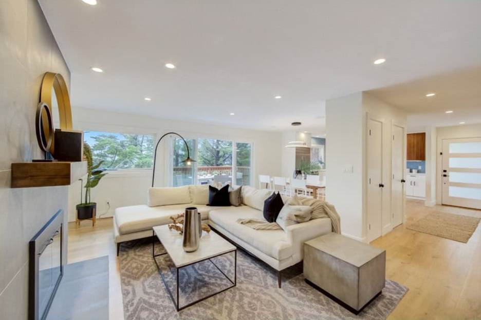 Back-to-School Prep: Bright modern open-concept living room with a white sectional sofa, marble coffee table, fireplace, and hardwood floors leading into the dining area.