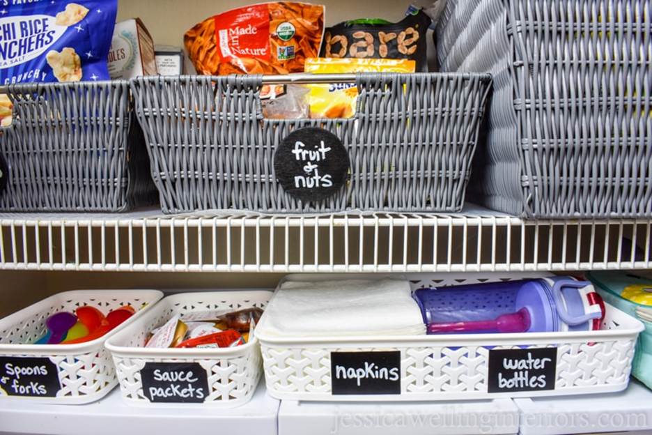 Back-to-School Prep: An organized pantry wire shelf featuring grey woven snack baskets and white plastic organizer bins with chalkboard labels for lunch prep essentials.