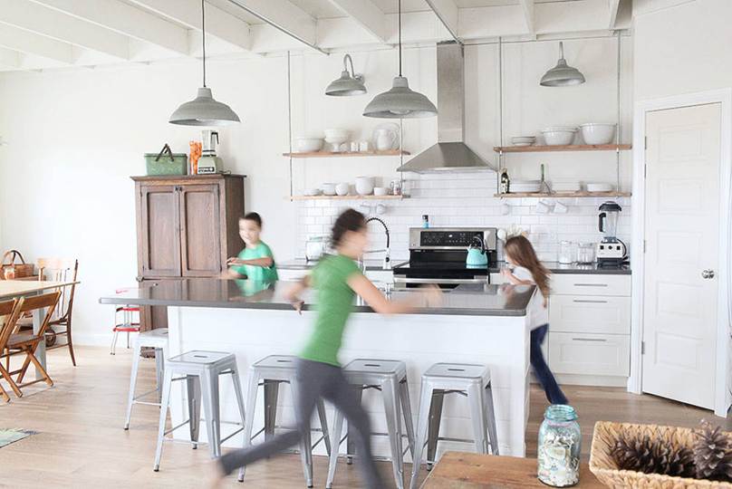 Kids playing and running around a bright kitchen island needing a recurring clean