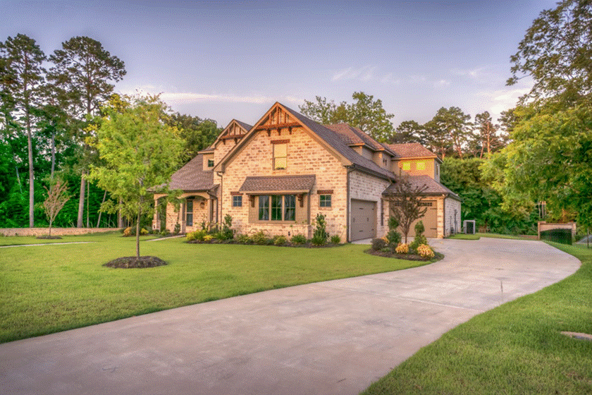 Front Porch Cleaning: Craftsman-style stone house surrounded by tall pine trees and a large green lawn at golden hour.